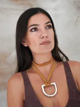 Collar con tira de cuero color suela y dije metálico dorado en forma de estribo.