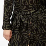 Vestido camisero midi de manga larga con estampado abstracto en tonos verde oliva y negro. Tiene cuello camisero, cierre frontal con botones dorados y cinturón de lazo.