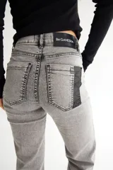 Pantalón de jean gris de corte acampanado, con tiro alto y costuras verticales al frente.