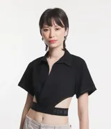 Camisa corta negra con cuello camisero, mangas cortas y aberturas laterales con elástico con letras blancas.