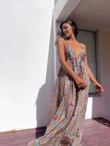 Vestido largo con estampado paisley en tonos marrones, celestes, dorados y fucsias. Tiene escote halter con tirantes finos y bordados rojos en el frente.