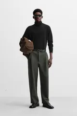 Pantalón relaxed fit color verde oscuro, con pliegues en la parte delantera, bolsillos laterales y traseros de ojal. Cierre frontal con cremallera y botón.