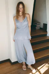 Top celeste semitransparente de escote pico y tirantes finos. Detalle de drapeado lateral ajustable con cordones.