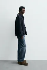 Pantalón de jean azul de corte recto, con cinco bolsillos, efecto lavado y cierre frontal con botones.