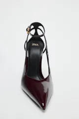 Zapato de tacón destalonado color borgoña, con efecto acharolado, tacón fino, cierre mediante hebilla en la pulsera al tobillo y acabado en punta.