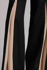 Pantalón ancho marrón con aberturas frontales que revelan un forro o panel interior de tela celeste. El pantalón se combina con un top a juego, creando un conjunto de dos piezas.