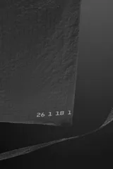 Bandolera negra de tejido técnico con correa ajustable, cierre con cremallera y detalle de texto y logo estampados.