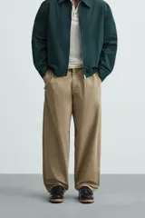 Pantalón color caqui de corte amplio, con pinzas en la cintura, bolsillos laterales y traseros con botón.