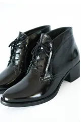 Botines acordonados de cuero charol negro, con tacón bloque y puntera ligeramente puntiaguda.