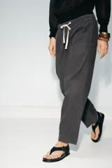 Pantalón de tiro medio con cintura elástica ajustable con cordones, bolsillos laterales ocultos en costura y pierna ancha. Confeccionado en hilatura con algodón y lyocell.