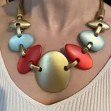 Collar corto con piezas ovaladas unidas con eslabones dorados, combinando dorado, coral y turquesa.