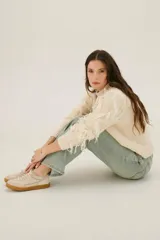 Pantalón de jean azul de corte acampanado, con bolsillos delanteros y traseros, y detalle de cuero sintético en la cintura.