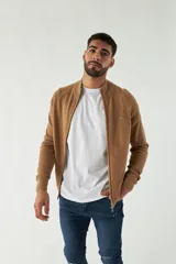 Campera tejida color marrón claro, con cuello alto, cierre frontal completo y mangas largas.