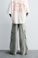 Pantalón relaxed fit de denim negro con efecto lavado, bolsillos frontales, traseros de plastrón y multifunción en perneras. Bajo ajustable con trabilla y cierre frontal con cremallera y botón.