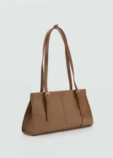 Bolso tipo tote de color crema, con efecto piel, forro interior, asa corta y asa de hombro. Tiene cierre a presión y cierre de cremallera, bolsillo interior y hebillas decorativas.