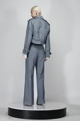 Conjunto de chaqueta corta y pantalón de denim color celeste con sutiles destellos. La chaqueta es corta, estilo motociclista con cierre cruzado y cinturón. El pantalón es de tiro alto y corte recto.