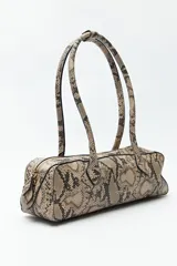 Cartera baguette color marrón claro, confeccionada en símil cuero con formato cilíndrico y doble asa corta.