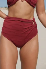 Bombacha de bikini tiro alto, corte vedetina, color ladrillo, con argolla decorativa de resina y forro interno.