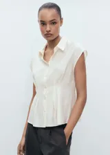 Camisa color crema con cuello camisero, manga corta y pinzas en la cintura.