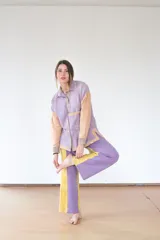 Camisa lila con mangas color beige, de silueta relajada confeccionada en paño de lana suave. Tiene canesú amplio, bolsillo delantero y aberturas laterales que aportan movimiento.