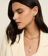 Conjunto de accesorios de tres piezas con baño dorado claro. Incluye una cadena de eslabones, un collar con colgante de cristal transparente y un par de caravanas de argolla con colgantes de cristal coordinados.