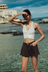 Short de denim color marrón oscuro, de tiro alto, con cinco bolsillos, calce holgado y bajo desflecado.