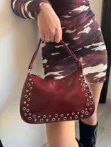 Cartera de cuero color borgoña con tachas plateadas.