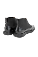 Botín Chelsea negro de cuero vacuno liso con inserciones elásticas laterales y detalle texturizado en el talón.