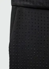 Pantalón largo acampanado negro con strass, tiro medio, bolsillos laterales y cierre oculto de botón, gancho y cremallera.