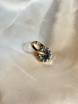 Arito dorado con forma circular, centro negro y strass blancos alrededor. Se vende por unidad.