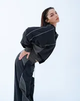 Pantalón deportivo negro con recortes en gris y vivos blancos. Tiro medio, corte holgado, cintura elastizada y cierre en los tobillos.