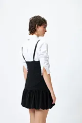 Vestido corto de lurex plateado y negro, sin mangas, con breteles finos regulables y volados tipo balloon desde la cadera.