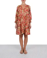 Vestido corto con estampado floral en tonos naranja, amarillo y blanco. Tiene escote en V, mangas 3/4 abullonadas y cierre frontal con botones.