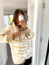 Buzo de poliéster color beige con estampado de leopardo blanco, cuello alto con botones a presión y bolsillos laterales.