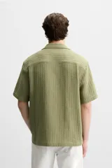 Camisa verde oliva de manga corta con cuello bowling, corte relaxed fit y cierre frontal con botones.