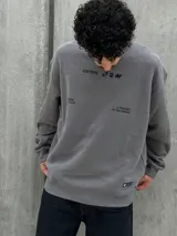 Buzo gris con cuello redondo, mangas largas y puños y bajo acanalados. Estampado frontal con el logo "Osten" y la frase "A mindset of becoming".