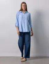 Camisa celeste de lino, con cuello con solapa, escote en V y abertura central con botones. Largo de manga regulable con presilla y botón. Delantera con bolsillo aplicado.