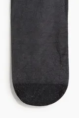 Medias de lycra negras transparentes con hilos plateados brillantes en la trama y cintura elástica estándar.