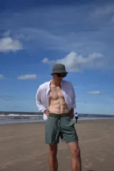 Short de baño verde con estampado de hojas y flores en tonos verde oscuro y marrón. Tiene bolsillos laterales y traseros, cintura elástica con cordón ajustable y corte clásico.