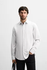 Camisa celeste de corte slim fit, confeccionada en tejido de algodón. Tiene cuello italiano, mangas largas con puños abotonados y cierre frontal con botones.