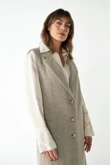 Chaleco largo color crema de lana fina sin mangas, con solapas y cierre frontal con tres botones. Presenta bolsillos ojal.