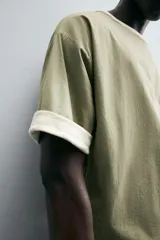 Camiseta color verde claro, de corte holgado, confeccionada en tejido de algodón con interior reversible de popelín. Tiene cuello redondo, manga corta y acabados con vivo combinado a contraste.
