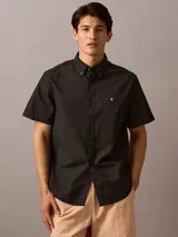 Camisa negra de manga corta, corte clásico, con cuello abotonado y logo de Calvin Klein bordado en el pecho.