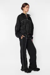 Campera negra oversize con combinación de textil deportivo y sastrero, cierre metálico YKK desmontable, elástico en puños y cintura, vivo a contratono en mangas y cuerpo, forrada al tono.