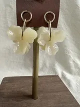 Aros colgantes con forma de flor color crema y detalles dorados.