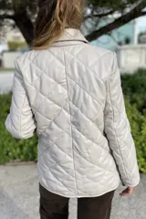 Campera de cuero negra con diseño matelassé de rombos, cuello camisero, cierre frontal con botones a presión, dos bolsillos delanteros y puños con botón.