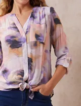 Blusa estampada con cuello a la base, escote en V y botones. Delantera con bolsillo aplicado. Largo de manga regulable con presilla y botón. Terminación anudada opcional.