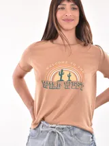 Remera color ladrillo con estampa de cactus y arcoíris con la frase "Welcome to the Wild West".