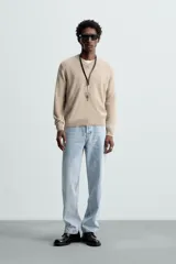 Jersey de punto color beige, con cuello en V y mangas largas.