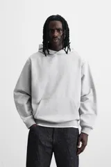 Sudadera con capucha gris confeccionada en tejido de algodón con interior rizo. Tiene manga larga, bolsillo frontal tipo canguro y acabados en rib.